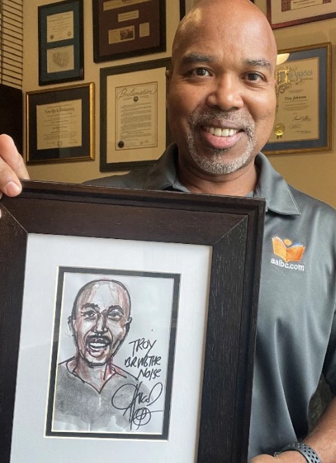 Pictured is AALBC founder Troy Johnson with his original, one-of-a-kind custom portrait by Chuck D.